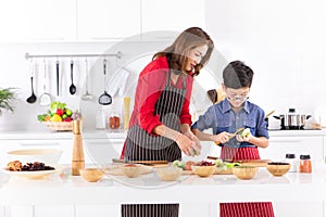 Asian family mom in red shirt and black apron is teaching her s