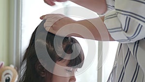 Asian family with mother combing her little girl.