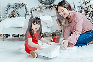 Asian family mother giving gift box with present to daughter toddler girl celebrating Christmas or New Year