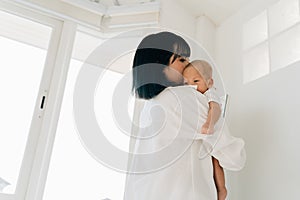 Asian family of mother holding a newborn baby boy over mom shoulder at home