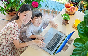 Asian family mpther and her son play and enjoy with computer notrbook