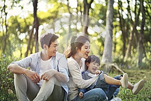 Asian family with one child relaxing outdoors
