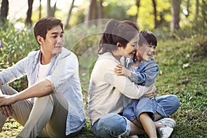 Asian family with one child relaxing in park