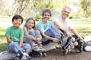 Asian Family Putting On In Line Skates In Par