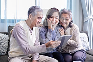 Asian family reunion of senior father, mother and daughter sitting on couch with happy smile in retirement home while looking at