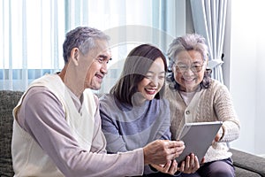 Asian family reunion of senior father, mother and daughter sitting on couch with happy smile in retirement home while looking at