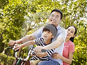 Asian family riding bike in park