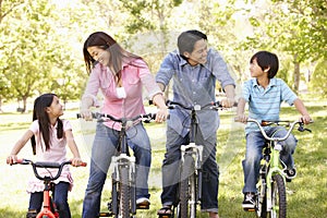 Asian family riding bikes in park