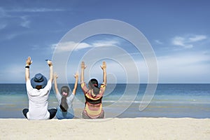 Asian family sitting relaxing on white sand beach with turqouise blue sea in sunny day photo