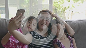 Asian Family Taking Selfie With Smartphone At Living Room.