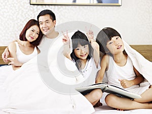 Asian family with two children having fun in bedroom