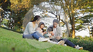 Asian family with two children relaxing outdoors in city park