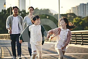 Asian family with two children taking a walk in city park