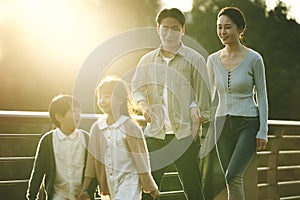 Asian family with two children taking a walk in city park