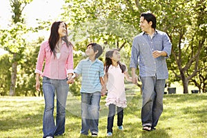 Asian family walking hand in hand in park