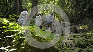 Asian family walking together in tropical forest and enjoy to see beautiful scenery of small waterfall during summer.