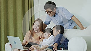 Asian family watching a laptop on the sofa