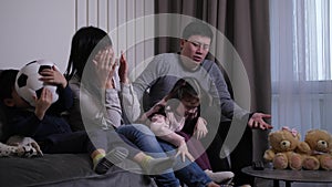 Asian family watching soccer game in domestic room