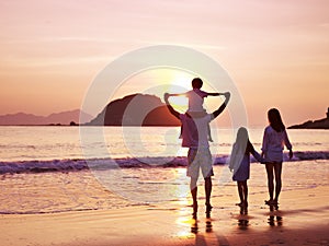 Asian family watching sunrise on beach