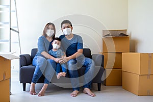 Asian family wearing protective medical mask for prevent virus covid-19 during moving day and relocating at new home.