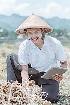 Asian farmer smiled while showing the rice crop yields when using a tablet