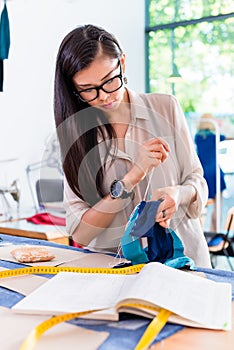 Asian fashion designer woman sewing in her workshop