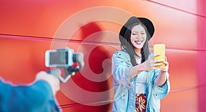 Asian fashion woman vlogging and using mobile smart phone outdoor - Happy Chinese trendy girl having fun making video