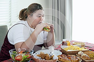 Asian fat girl hungry and eat a junk food on the table photo