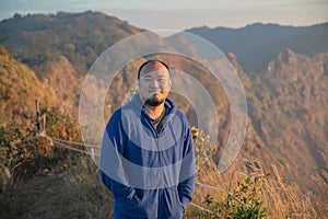 Asian fat man with beautiful sunrise of khao San nok wua mountain kanchanaburi.