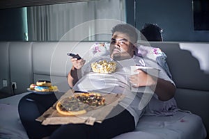 Asian fat man eating junk foods on the bed