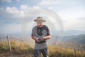 Asian fat man holding camera tripod with beautiful view of khao San nok wua mountain kanchanaburi.