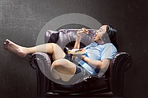 Asian fat man snacking donuts on the couch