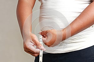 Asian fat men use waist tape measure to check the size.