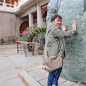 Asian fat traveler touch the Big spirit stone in jian an temple shanghai city