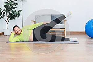 Asian fat woman doing exercise at home by stretching the leg muscles