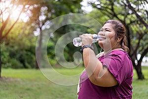 Asian fat woman drinking water bottle with workout outdoors exercising in park,