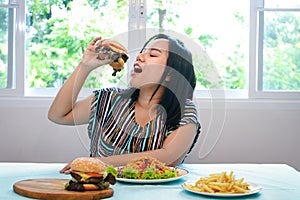 Asian fat woman sitting at the dining table I`m eating a hamburger