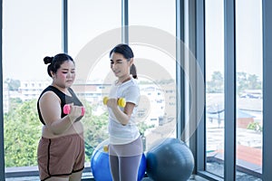 Asian Fat woman and trainer work out in the fitness class and The trainer recommends exercise for weight loss for obese women