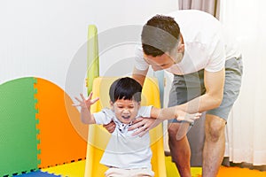 Asian father accompanying child on the playground slider at home. Happy family with toys. photo