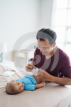 asian father changing his infant baby diaper