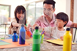 Asian Father With Children Having Fun With Children Doing Craft On Table At Home