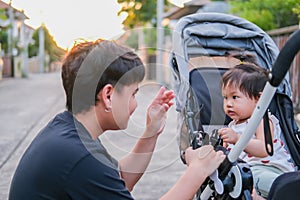 Asian father and daughter or son cute girl making play feeling happy and enjoy on baby stroller father and son eye contact smile