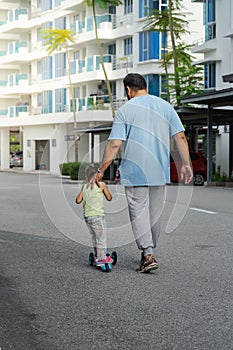 Asian father and daughter walking  and playing on the road at the day time. People having fun outdoors. Concept of friendly family