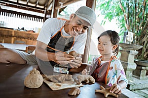 Asian father and daughter working with clay