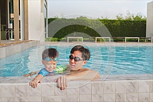 Asian Father holding cute little Asian toddler boy child on the edge of a swimming pool, Happy dad and son spending time together