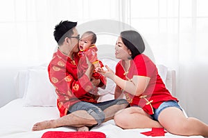 Asian father  mother hold son toddler boy on bed at home with love  Chinese new family in red Chinese costume give envelope to