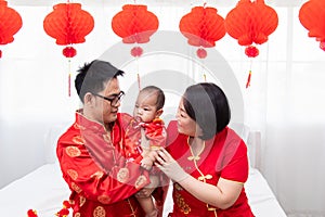 Asian father  mother hold son toddler boy on bed at home with love  Chinese new family in red Chinese costume give envelope to