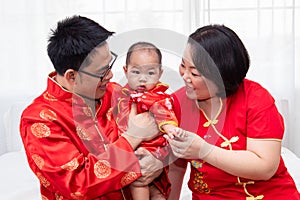 Asian father  mother hold son toddler boy on bed at home with love  Chinese new family in red Chinese costume give envelope to