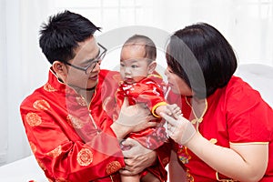 Asian father  mother hold son toddler boy on bed at home with love  Chinese new family in red Chinese costume give envelope to