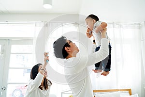 Asian father and mother lifting their little own son up flying in the air with laughter